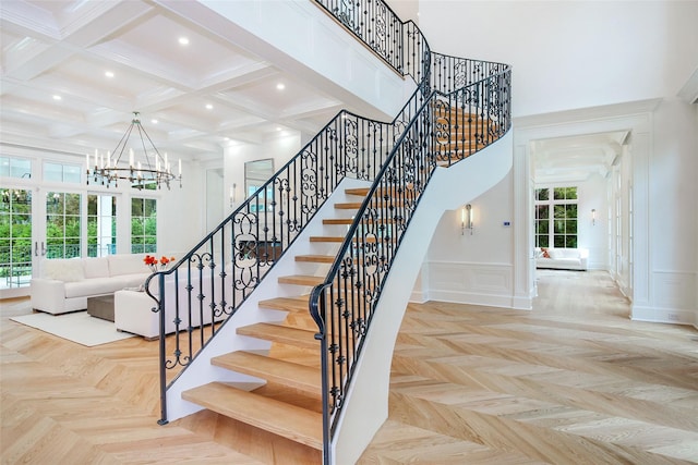 stairs featuring a notable chandelier, a high ceiling, a decorative wall, and a wealth of natural light