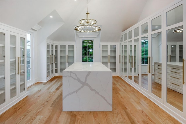 spacious closet featuring lofted ceiling, a notable chandelier, french doors, and light wood finished floors