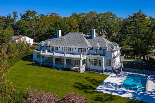 rear view of property featuring a yard, a fenced backyard, a fenced in pool, and a chimney