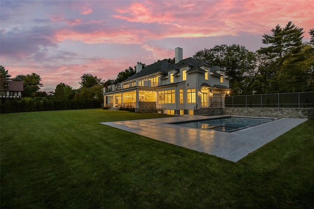 back of property featuring a lawn, a patio, fence, a fenced in pool, and an in ground hot tub