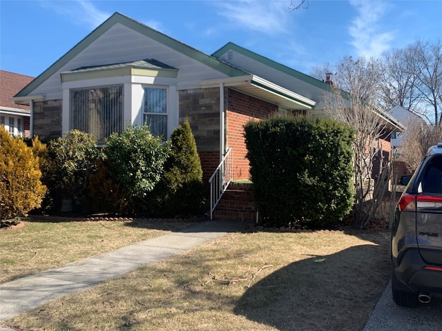 view of front of home featuring brick siding, stone siding, and a front yard