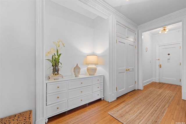 foyer with crown molding and light wood-style floors