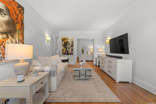 living area with ornamental molding, baseboards, and wood finished floors