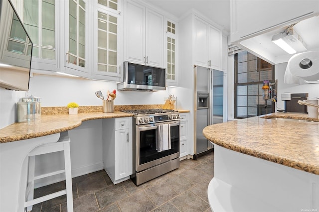 kitchen featuring white cabinets, light stone counters, appliances with stainless steel finishes, and a sink