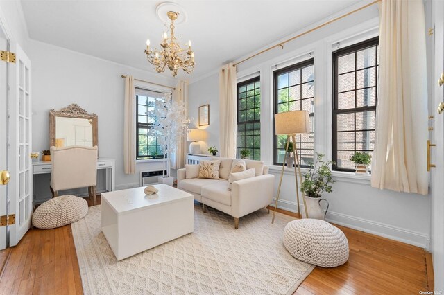 sitting room with hardwood / wood-style flooring, a notable chandelier, baseboards, and ornamental molding