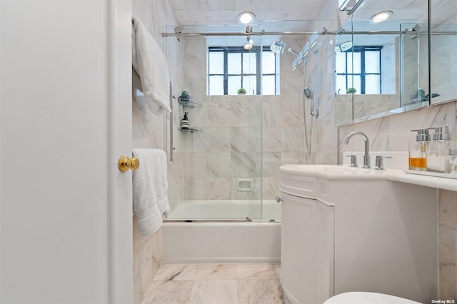 bathroom featuring vanity, toilet, marble finish floor, and shower / bath combination with glass door