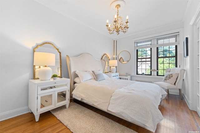 bedroom with an inviting chandelier, crown molding, baseboards, and light wood-type flooring