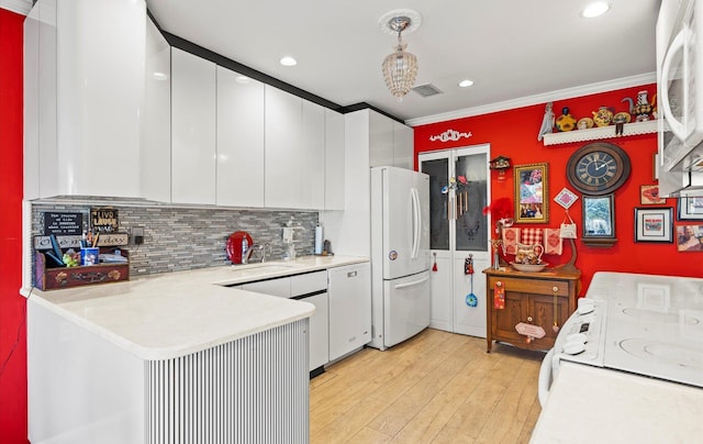 kitchen featuring light countertops, light wood-style flooring, a peninsula, white cabinets, and white appliances