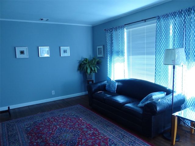 living area with visible vents, baseboards, wood finished floors, and crown molding