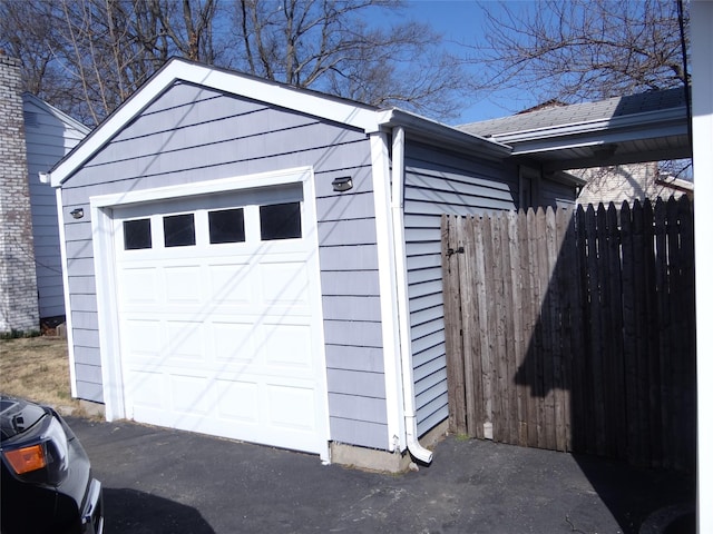 garage featuring aphalt driveway and fence