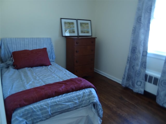 bedroom featuring radiator, baseboards, and wood finished floors