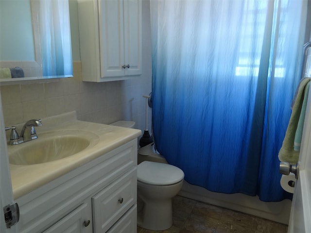 bathroom with shower / bathtub combination with curtain, toilet, tasteful backsplash, tile walls, and vanity