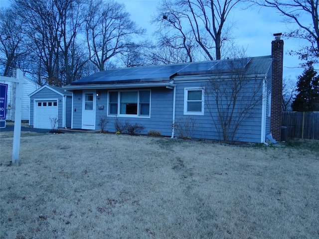 ranch-style house with solar panels, a front lawn, fence, and a chimney