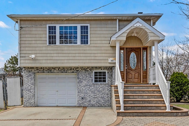 view of front of home with an attached garage, fence, brick siding, and driveway