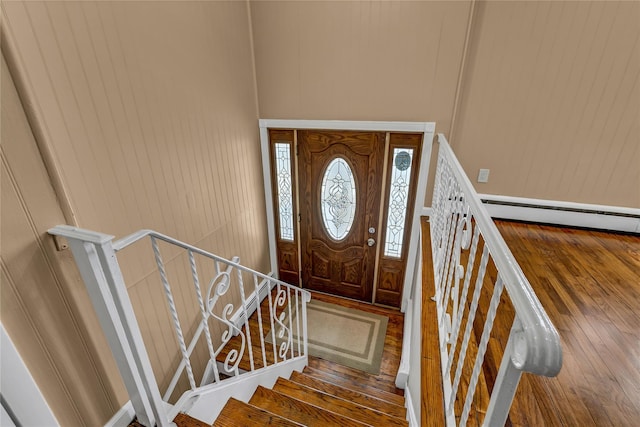 foyer with stairway, wood-type flooring, and baseboard heating