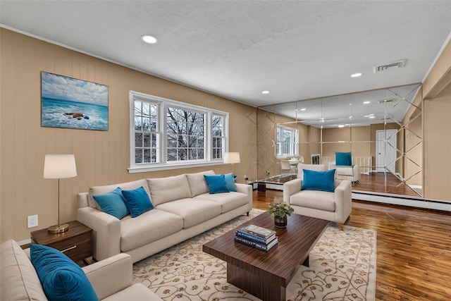 living room with visible vents, a textured ceiling, wood finished floors, recessed lighting, and baseboard heating