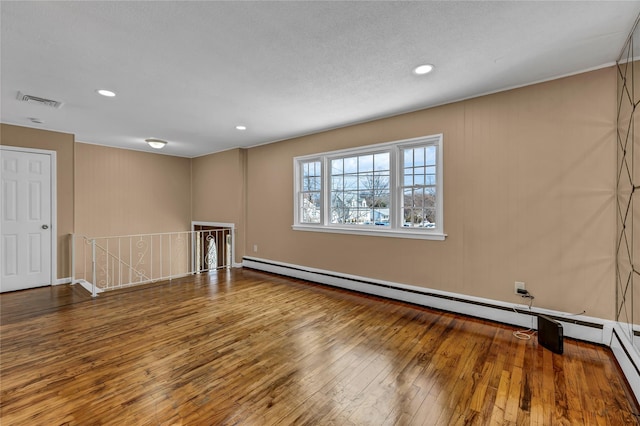 empty room with recessed lighting, visible vents, wood-type flooring, and a baseboard heating unit