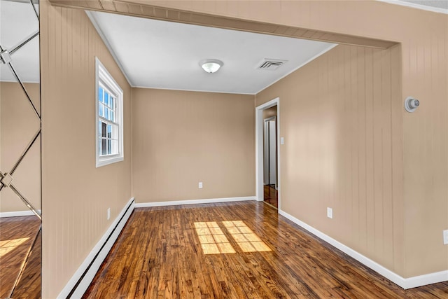 unfurnished room with baseboards, wood finished floors, visible vents, and a baseboard radiator