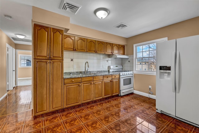 kitchen with visible vents, brown cabinets, white appliances, and a sink