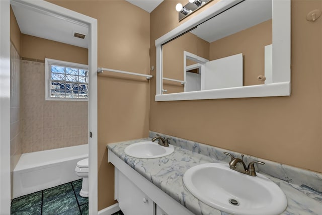 bathroom with double vanity, visible vents, toilet, and a sink