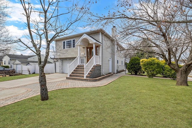 split foyer home featuring a front lawn, decorative driveway, fence, a garage, and a chimney