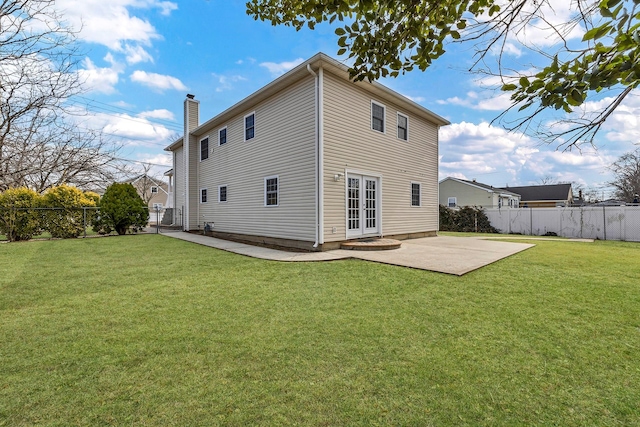 back of property with a fenced backyard, a lawn, french doors, and a patio