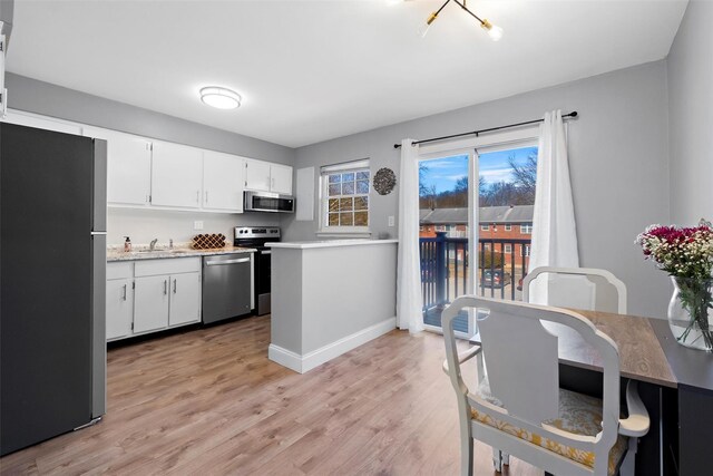 kitchen featuring a sink, light countertops, white cabinets, appliances with stainless steel finishes, and light wood-type flooring