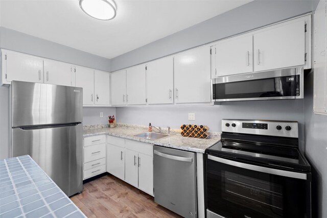 kitchen with a sink, light wood-type flooring, white cabinetry, and stainless steel appliances