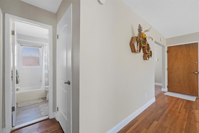 corridor featuring baseboards and hardwood / wood-style floors