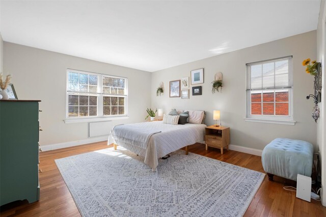 bedroom featuring baseboards, multiple windows, and wood finished floors