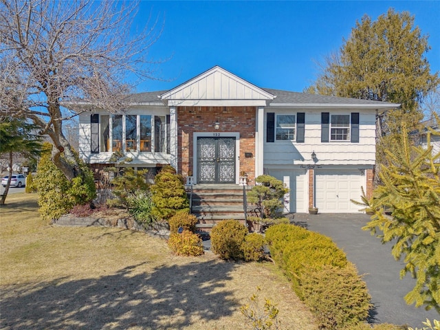 bi-level home with brick siding, french doors, a garage, aphalt driveway, and board and batten siding