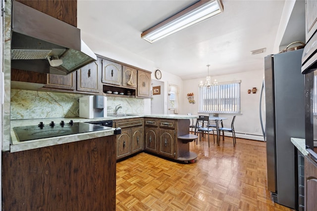 kitchen featuring under cabinet range hood, backsplash, freestanding refrigerator, a peninsula, and dark brown cabinets