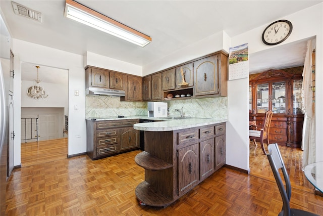 kitchen with under cabinet range hood, visible vents, open shelves, and dark brown cabinetry