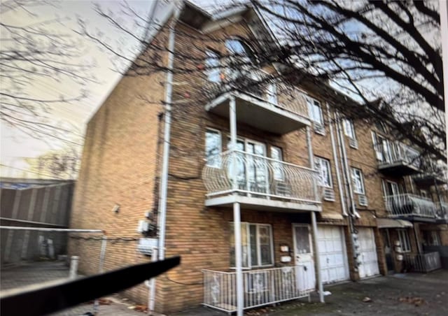 back of property featuring a garage, a balcony, and driveway