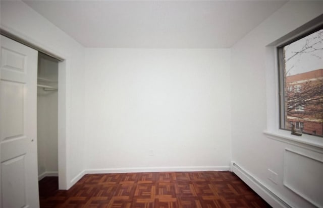 unfurnished bedroom with a closet, baseboards, and a baseboard radiator