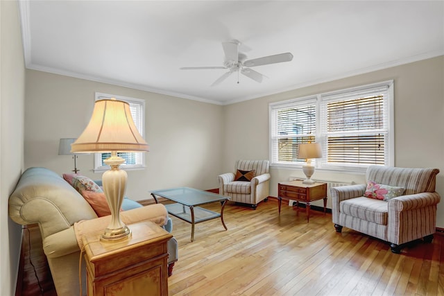 living area featuring a ceiling fan, light wood-style flooring, and crown molding