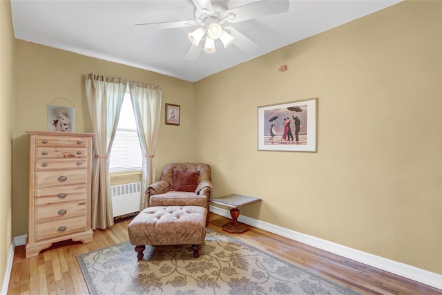 sitting room with baseboards, light wood-type flooring, radiator heating unit, and ceiling fan