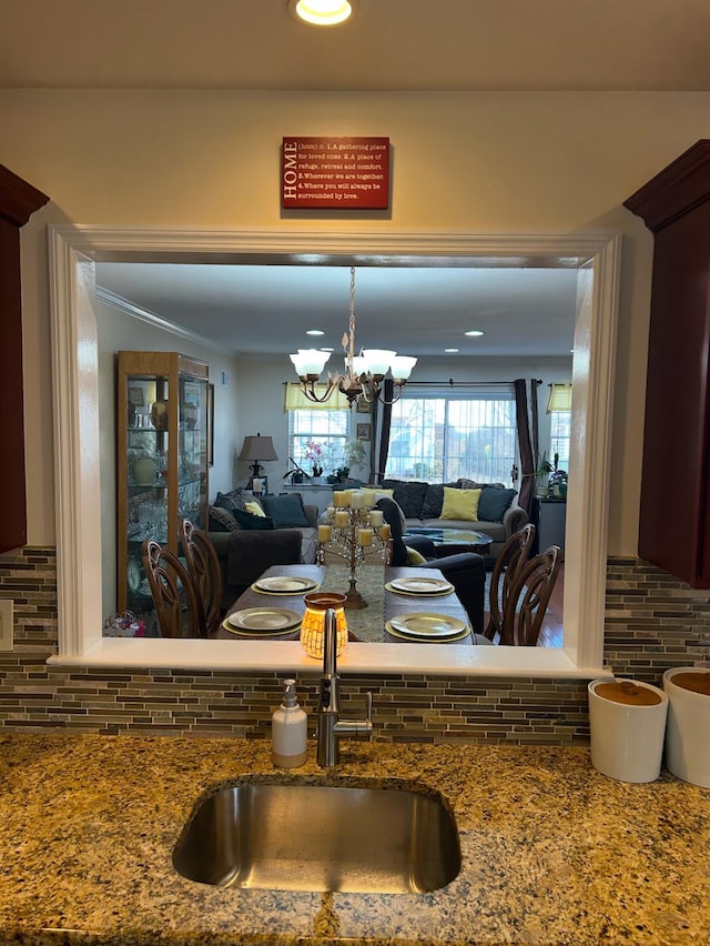 kitchen with a notable chandelier, decorative backsplash, open floor plan, and a sink