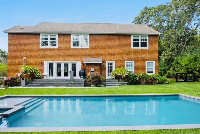 back of property with french doors, a lawn, entry steps, and a pool with connected hot tub