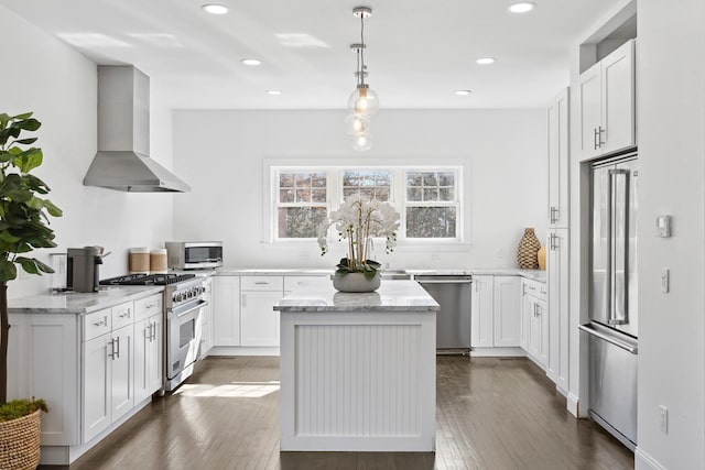 kitchen featuring a kitchen island, wall chimney range hood, light stone counters, white cabinetry, and high end appliances