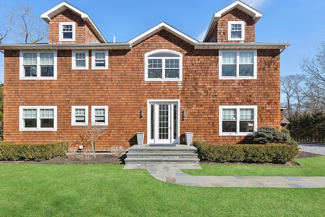 shingle-style home featuring a front lawn