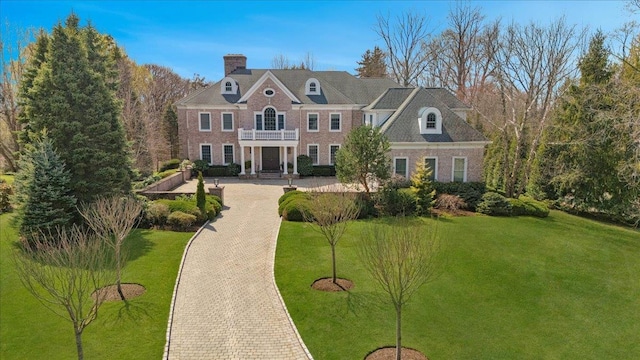6 Katsura Dr, Purchase, NY 10577 - colonial-style house with brick siding, a balcony, a chimney, and a front lawn