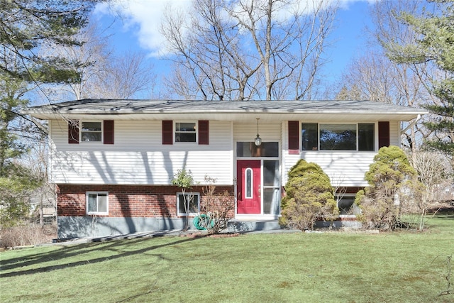 raised ranch featuring brick siding and a front yard