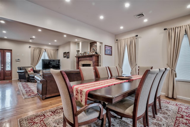 dining area featuring recessed lighting, visible vents, a brick fireplace, and light wood-style flooring