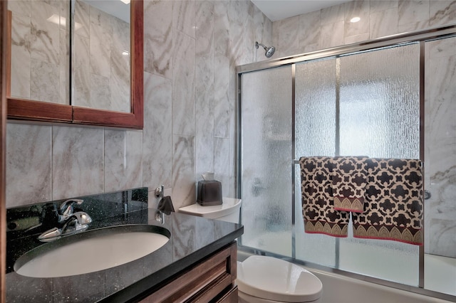 bathroom with vanity, tile walls, toilet, and enclosed tub / shower combo