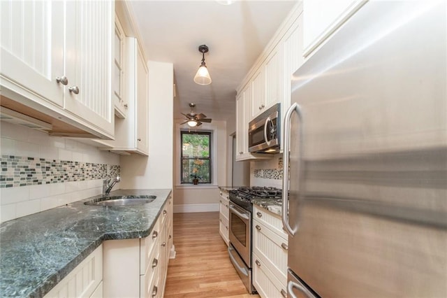 kitchen with tasteful backsplash, ceiling fan, light wood-type flooring, appliances with stainless steel finishes, and a sink