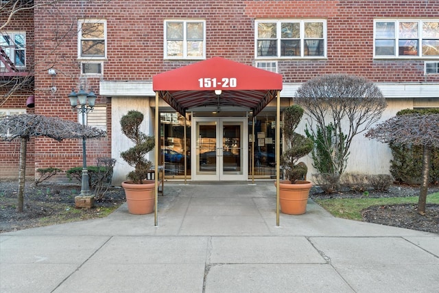 view of exterior entry featuring brick siding and french doors