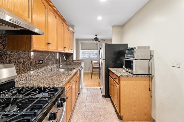 kitchen with a ceiling fan, a sink, decorative backsplash, extractor fan, and appliances with stainless steel finishes