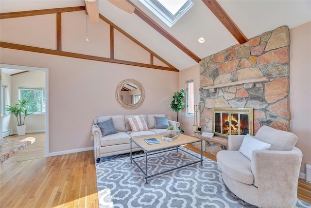 48 Crows Nest Dr, Baiting Hollow, NY 11901 - living area with beam ceiling, high vaulted ceiling, a skylight, wood finished floors, and a stone fireplace