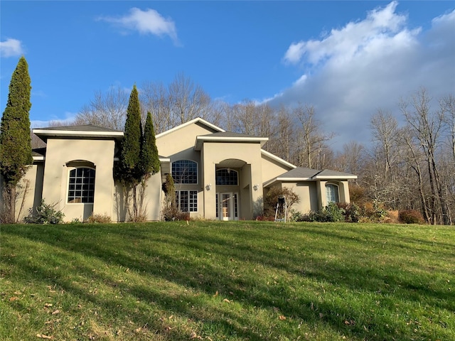 view of front of house with stucco siding and a front yard